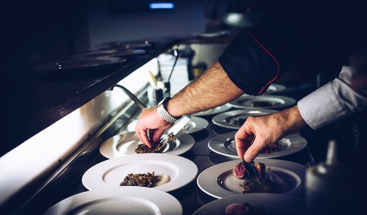 Chef plating a dish under the pass